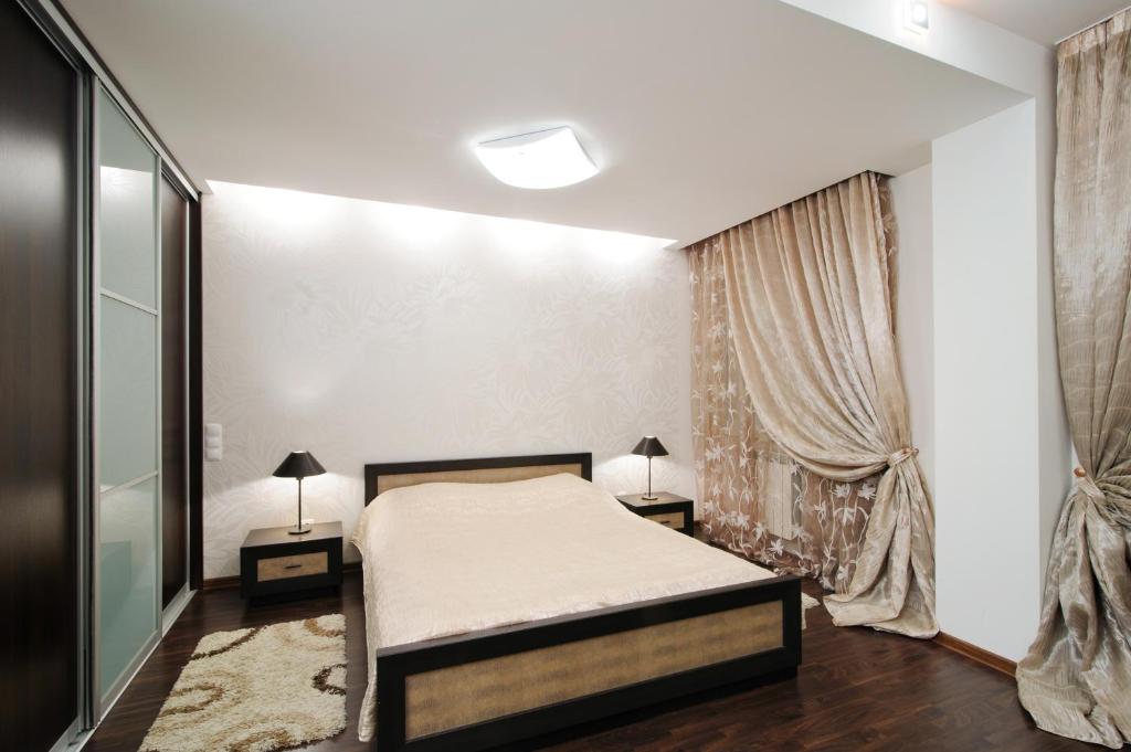 a bedroom with a bed and two lamps and a window at Centr kvartir 5 in Minsk