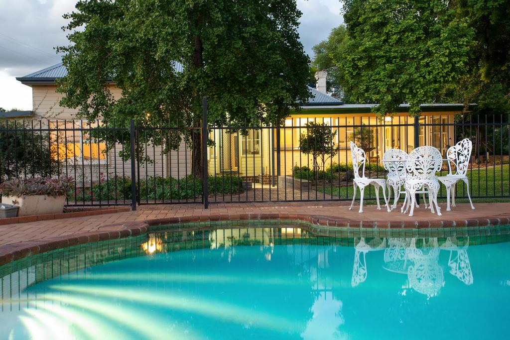 a pool with white tables and chairs next to a fence at Ivanhoe Park Homestead in Tamworth