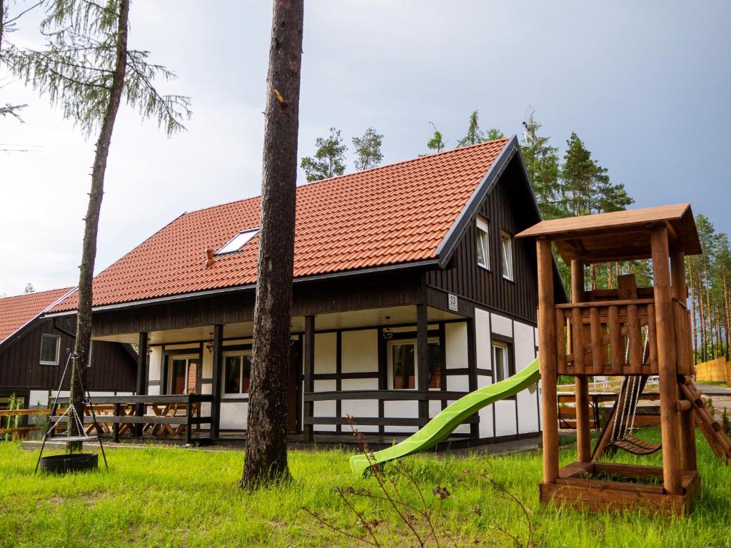 uma casa com um parque infantil em frente em Załakowo Na Gwizdówce 13 całoroczny domek na Kaszubach em Załakowo