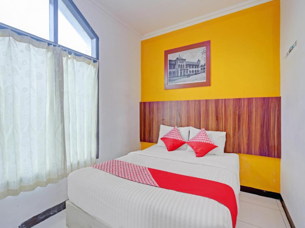 a bedroom with a bed with red and white pillows at OYO 90426 Near Mall Ciputra 2 in Semarang