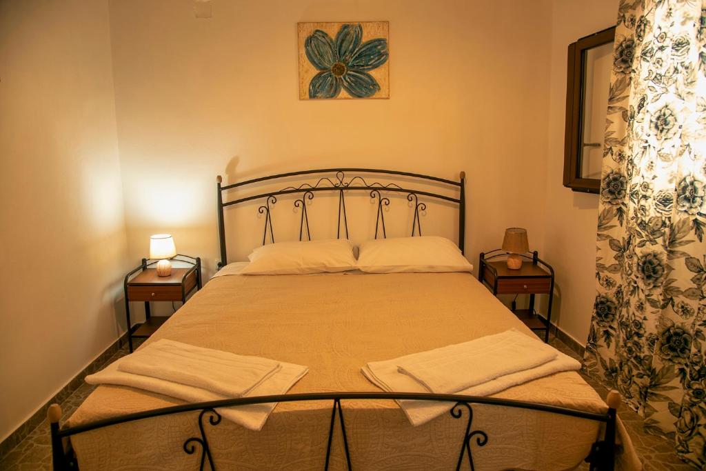 a bedroom with a bed with two nightstands and two lamps at flamingo colour valey house in Palekastron