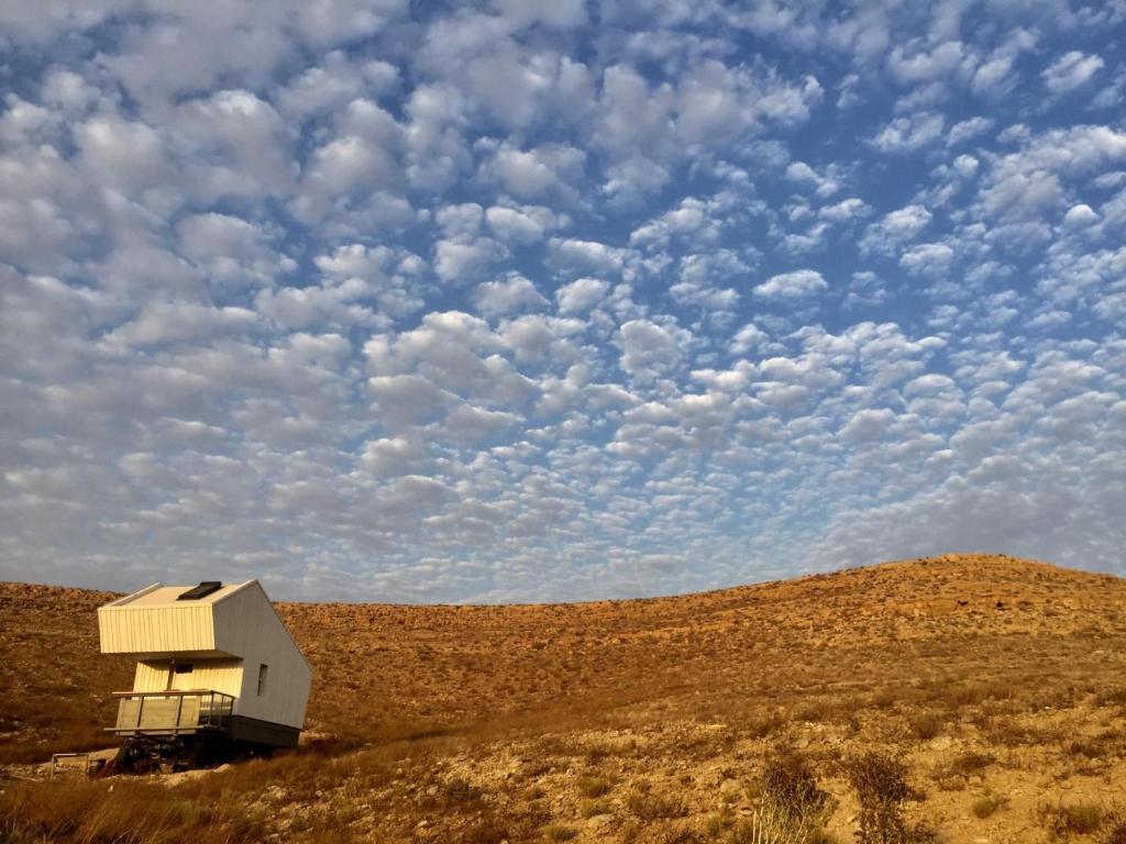 a small house on a hill in the middle of a field at פטריוט -יקב ננה in Mitzpe Ramon