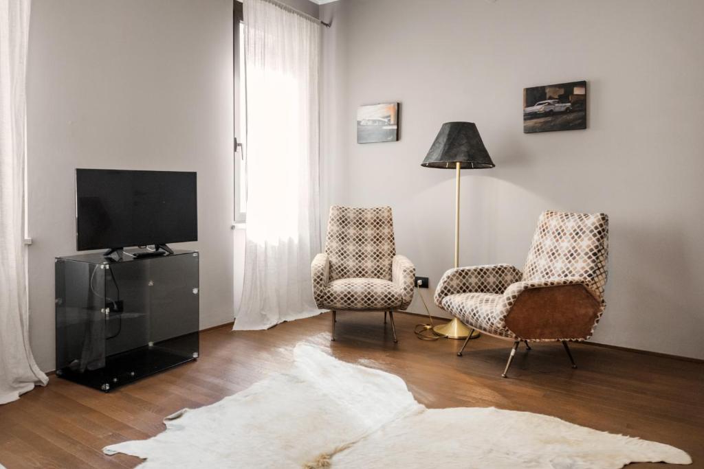 salon z 2 krzesłami i telewizorem z płaskim ekranem w obiekcie Flats4rent Al Monte w Weronie