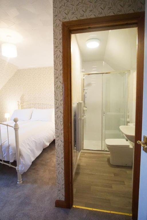a bedroom with a bed and a bathroom with a sink at Remuera, North Tolsta in North Tolsta