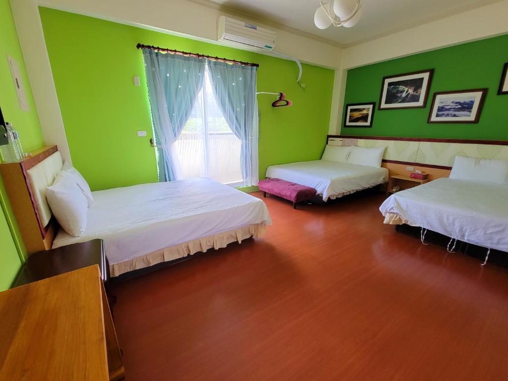 a green room with two beds and a window at 草莓牛奶台東民宿可洽包棟 in Taitung City