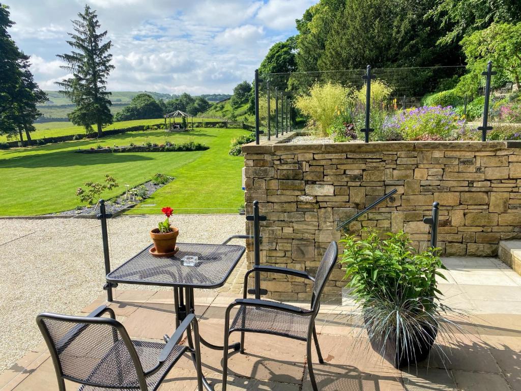 a patio with a table and chairs and a stone wall at Room with a View in Holmfirth