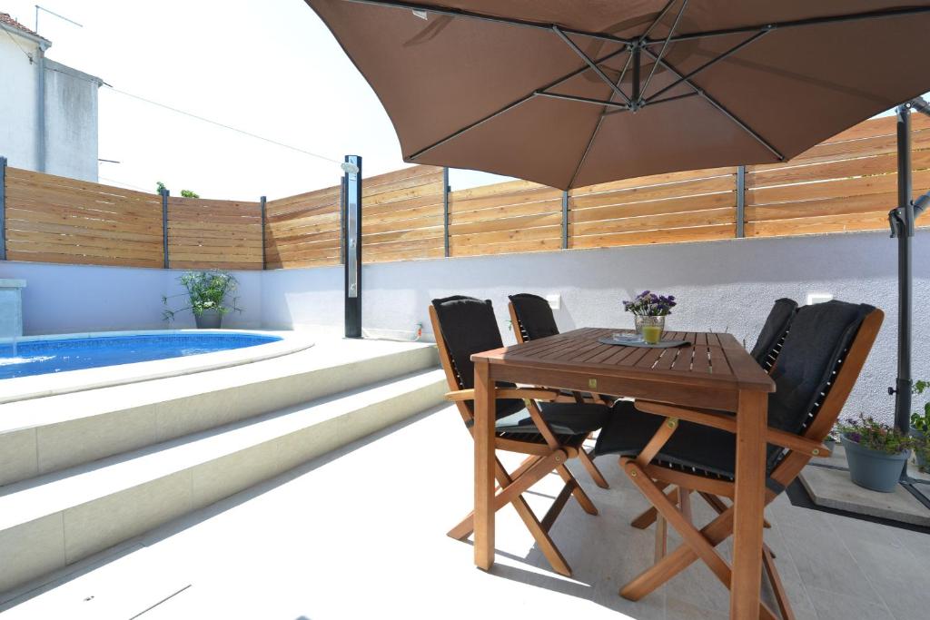 une terrasse avec une table et des chaises ainsi qu'une piscine dans l'établissement 2-Apartmans Villa PopandRock in Zadar, à Zadar