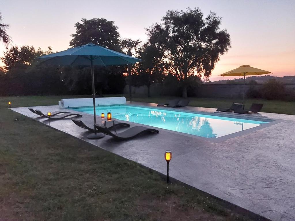 a swimming pool with an umbrella and chairs at Gite des vendangeurs 4 étoiles - 10 personnes in Bourg-sur-Gironde