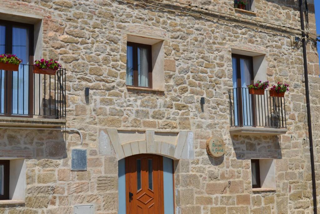 un antico edificio in pietra con finestre e porta in legno di Rincón de Guara a Bierge