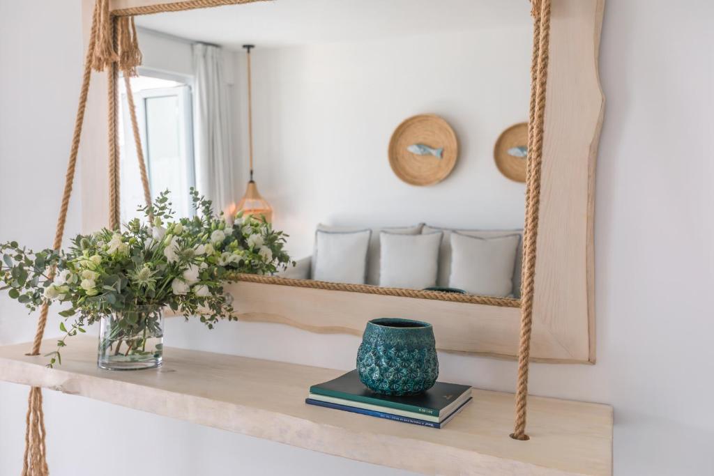 a mirror on a shelf with a vase and books at Blue Harbour Boutique in Ayia Napa