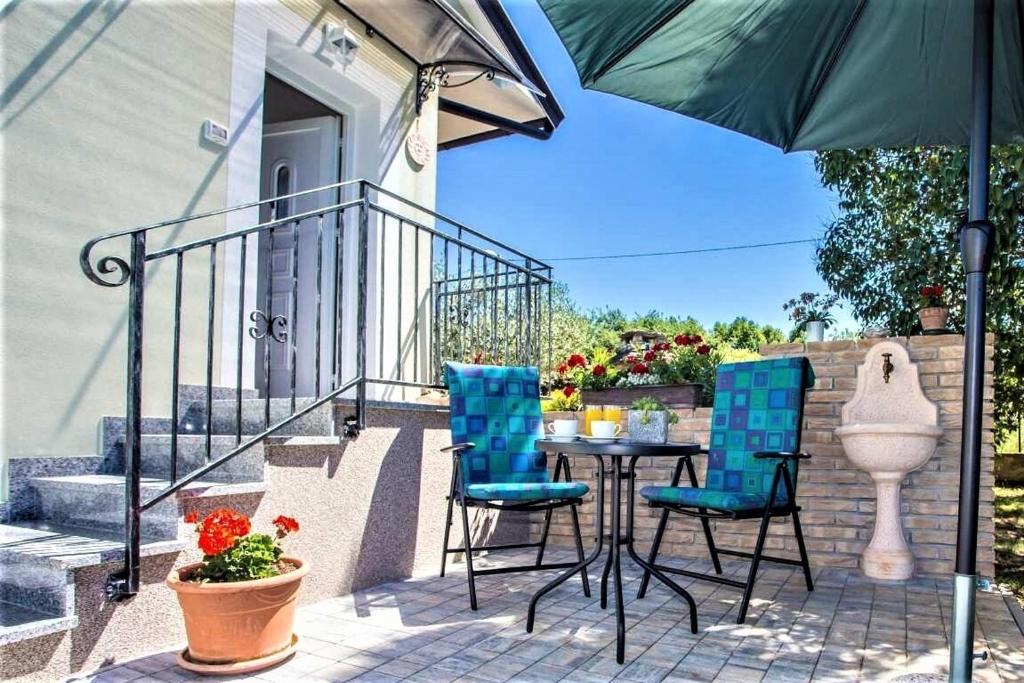 eine Terrasse mit einem Tisch, Stühlen und einem Sonnenschirm in der Unterkunft Apartment Green Oasis 1 in Umag