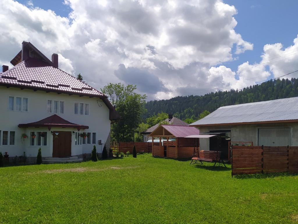 une maison blanche avec une cour à côté de deux bâtiments dans l'établissement Casa Moldovita, à Moldoviţa
