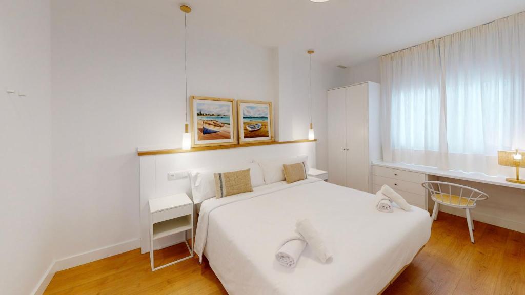 Un dormitorio blanco con una cama blanca y una ventana en Apartamentos La Casa El Palo en El Rompido