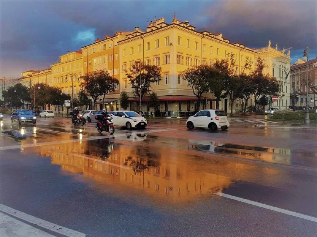 een stadsstraat met auto's geparkeerd voor een geel gebouw bij Residence Al Granzo in Trieste