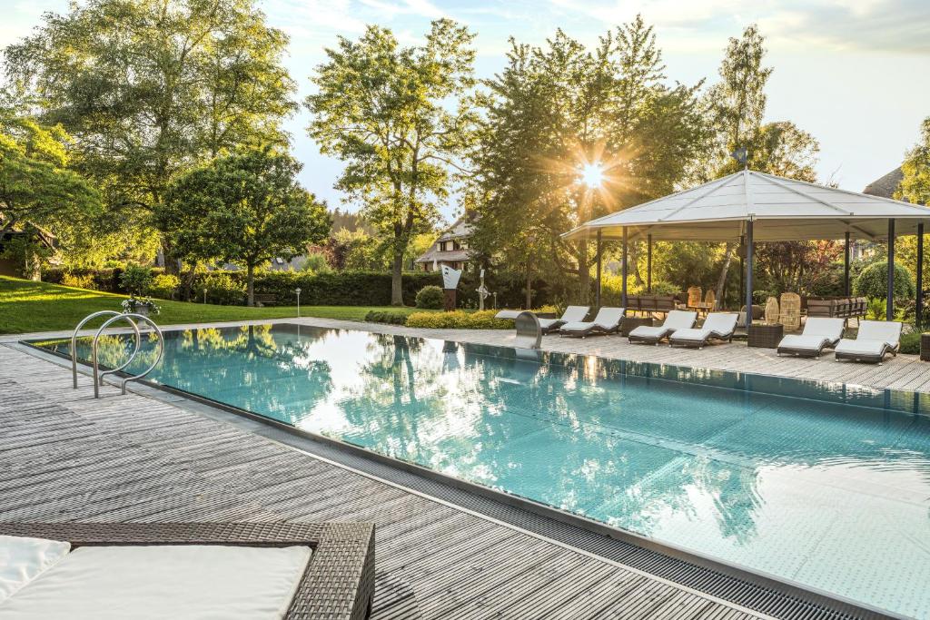 a swimming pool with chairs and a gazebo at Parkhotel Adler in Hinterzarten