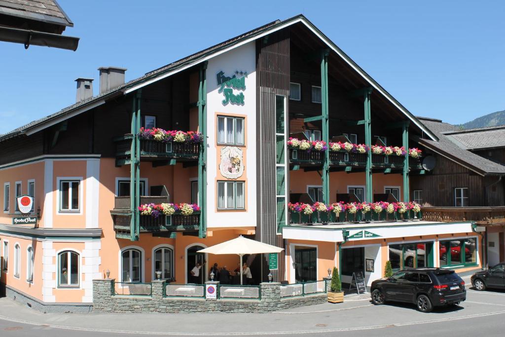 ein großes Gebäude mit Blumen auf den Balkonen darauf in der Unterkunft Hotel Post in Bad Mitterndorf