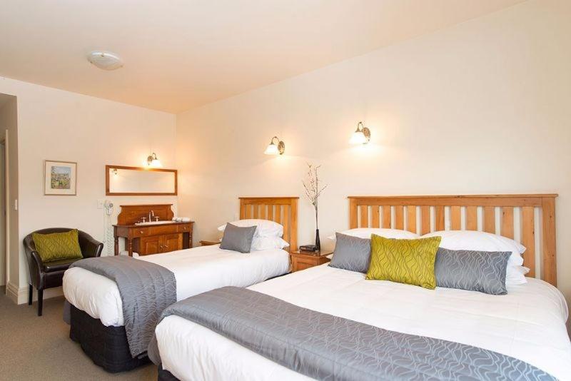 a hotel room with two beds and a desk at The Grand Hotel & Bar - Akaroa in Akaroa