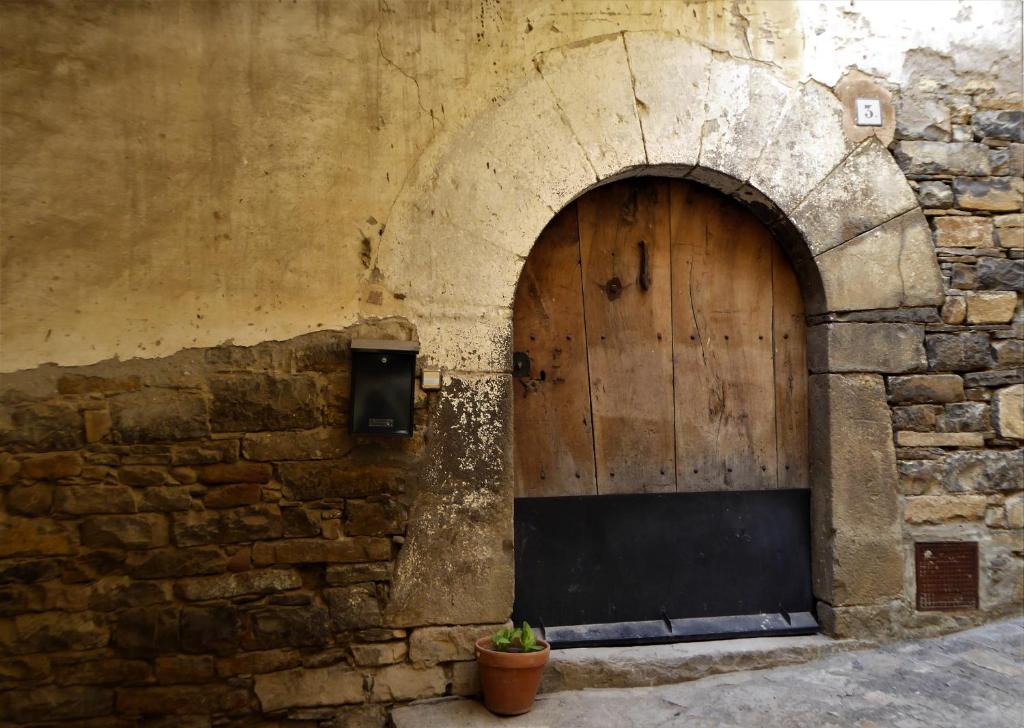 - un vieux bâtiment en pierre avec une porte en bois dans l'établissement Dos Arcos Usana, à Aínsa
