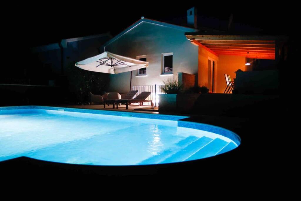 a large blue swimming pool at night with an umbrella at Casa Ro-Ma, seaside villa with a heated pool in Banjole