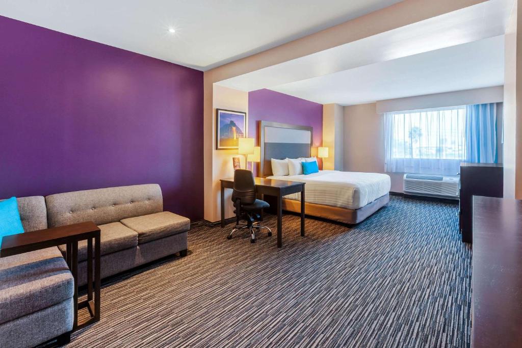 モンテレイにあるCHN Hotel Monterrey Aeropuerto, Trademark by Wyndhamのベッド、ソファ、デスクが備わるホテルルームです。