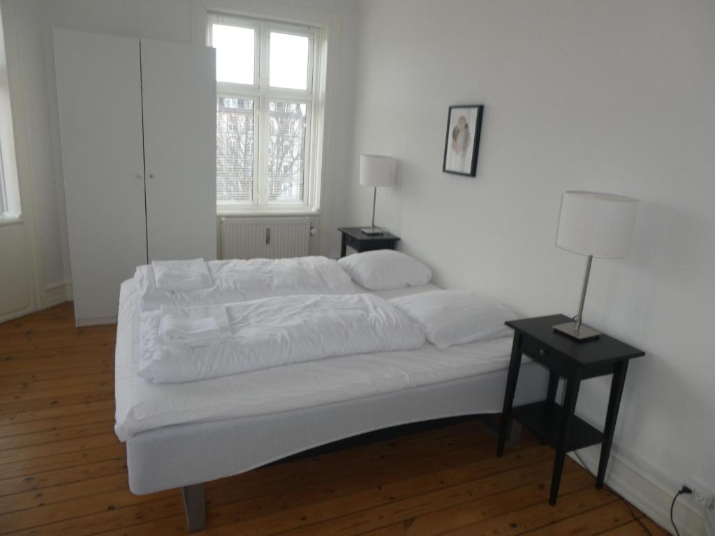 un letto bianco in una camera bianca con finestra di Bentzonsvej a Copenaghen