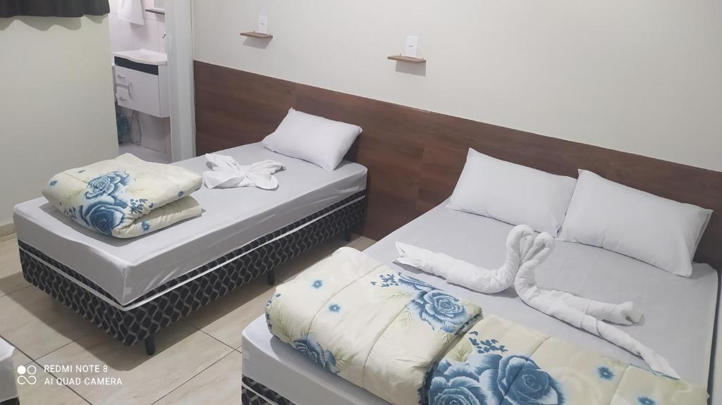 two beds in a room with white and blue at Pousada Quarto completo ar,wi fi e garagem gratuita in Aparecida