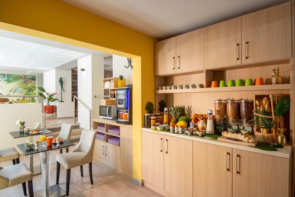a kitchen with wooden cabinets and a dining room at ibis Styles Beaulieu sur Mer in Beaulieu-sur-Mer