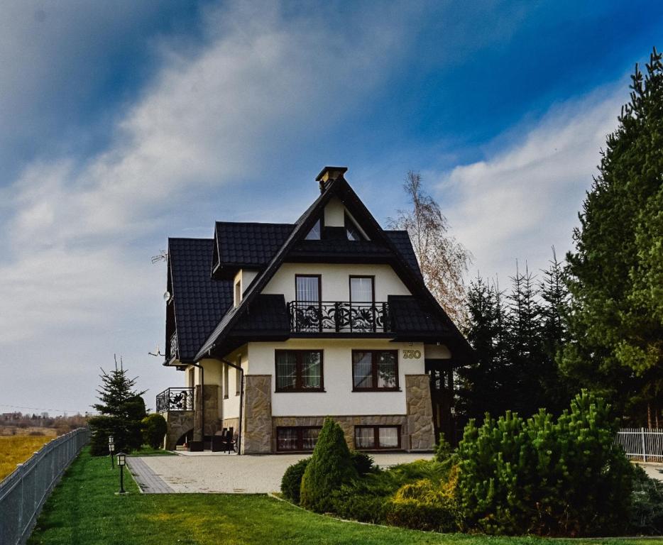 una casa blanca y negra con techo negro en Szymkówka, en Nowa Biała