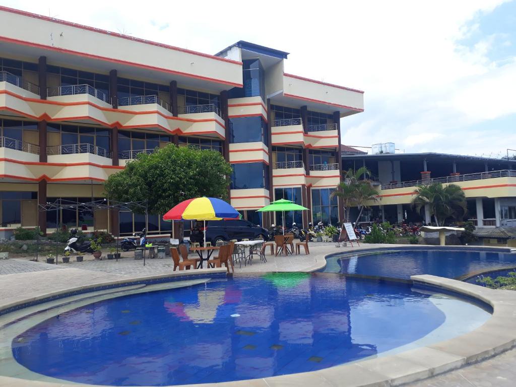 a hotel with a swimming pool in front of a building at Bukit Kenari Hotel & Restaurant in Parepare