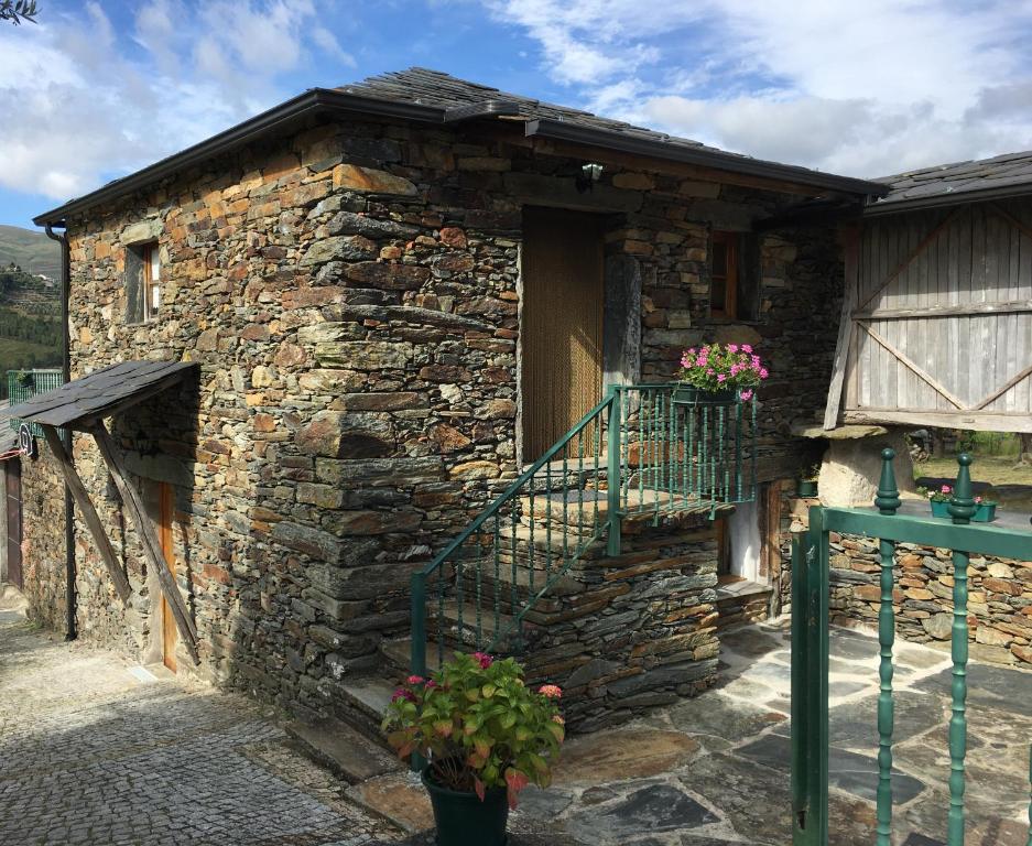 a stone building with a balcony and flowers on it at Palheiro do Vale do Paiva in Cabril