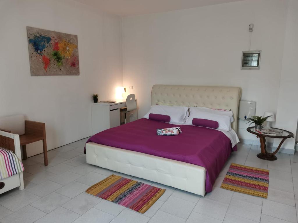 a bedroom with a large bed with a purple blanket at Bnbook Villa Biancospino in Travedona
