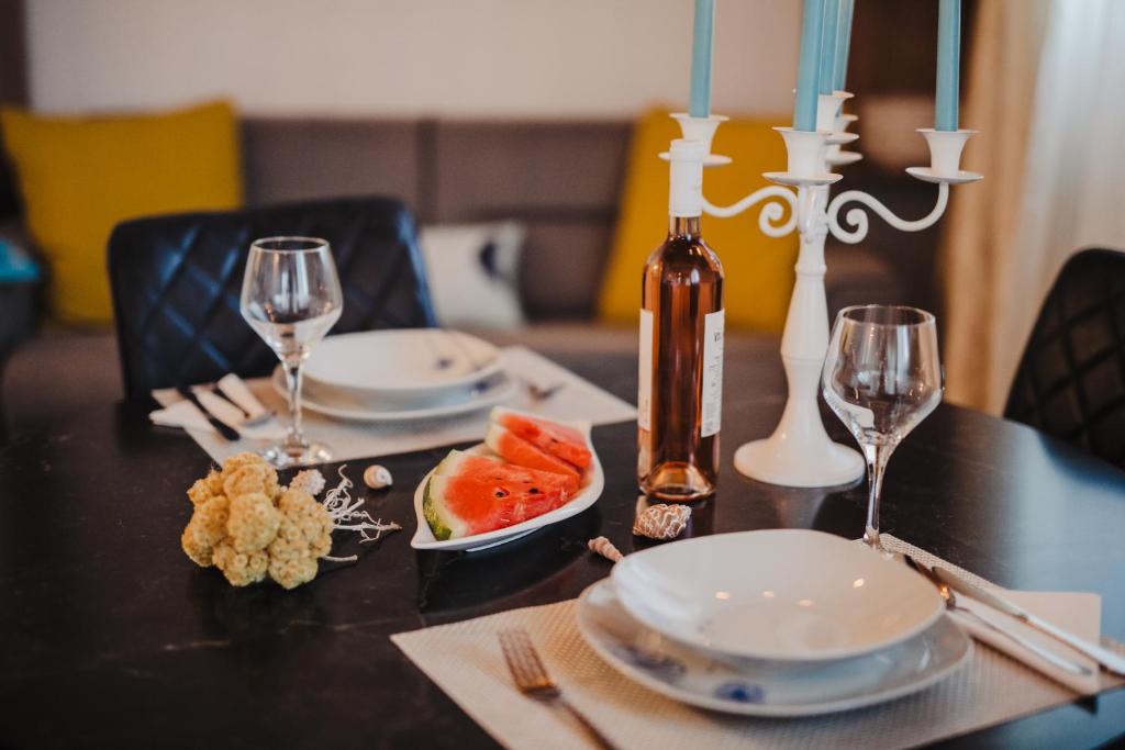 a table with plates and wine glasses and fruit on it at Studio apartmant Tonka in Šibenik