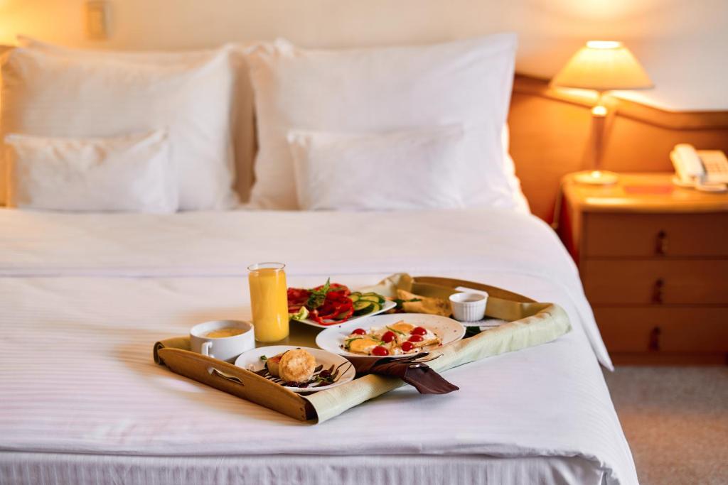 bandeja de comida en una cama en una habitación de hotel en Voznesensky Hotel, en Yekaterinburg