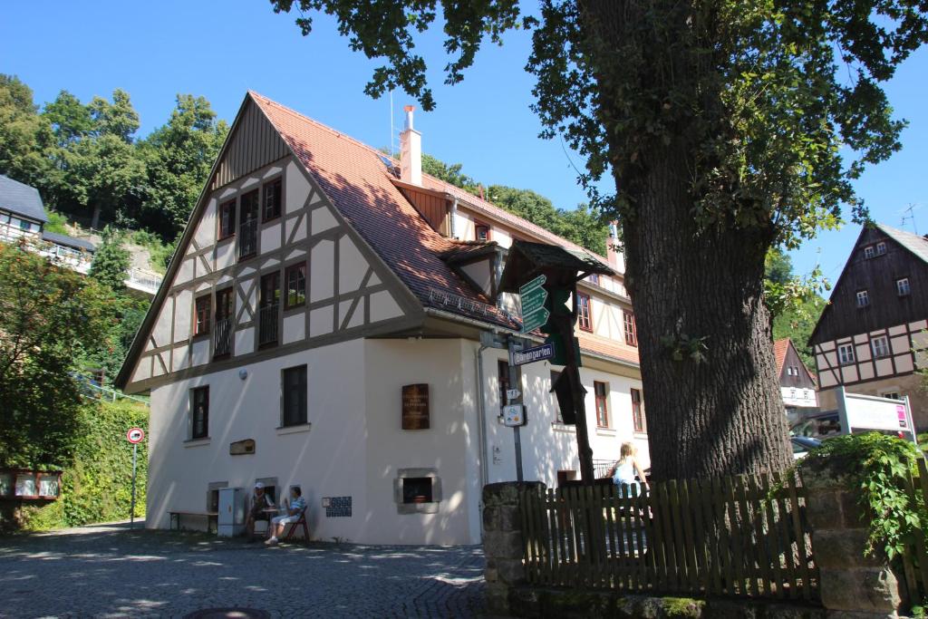 ein weißes Haus mit einem braunen Dach und einem Baum in der Unterkunft Gesundheitshaus Hohnstein in Hohnstein