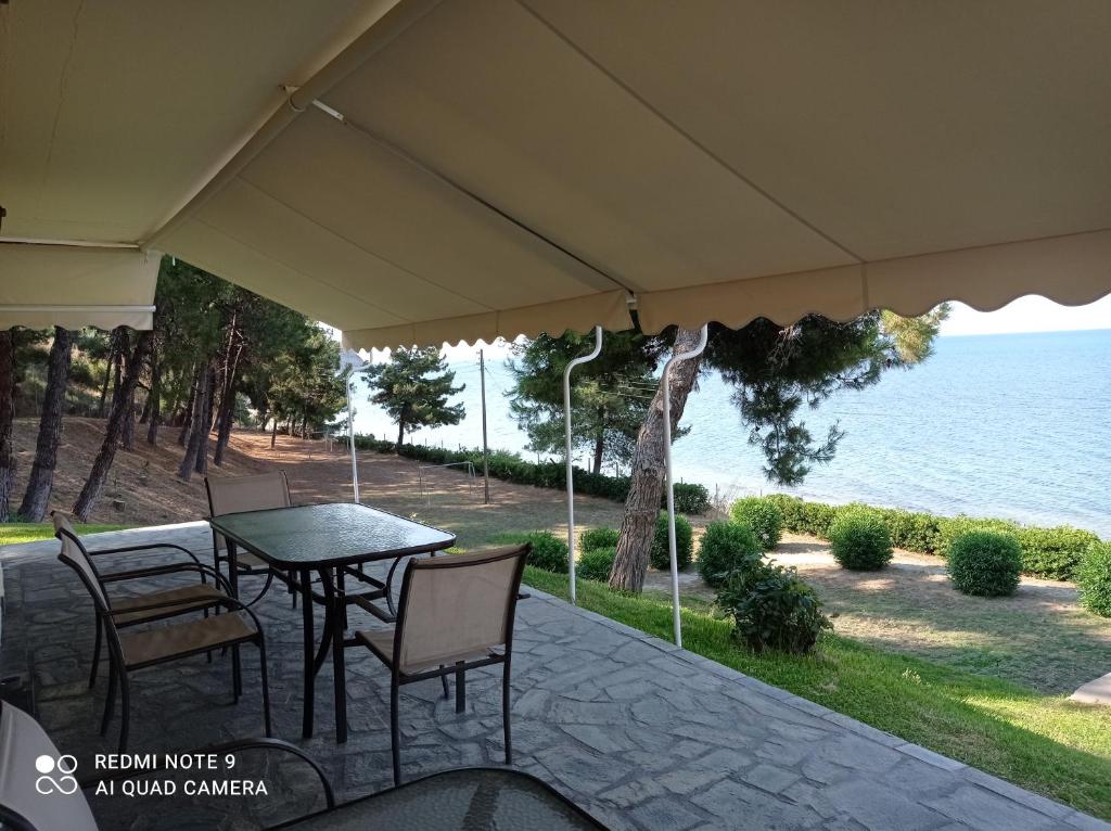 a patio with a table and chairs and the ocean at Sunset Apartment in Epanomi