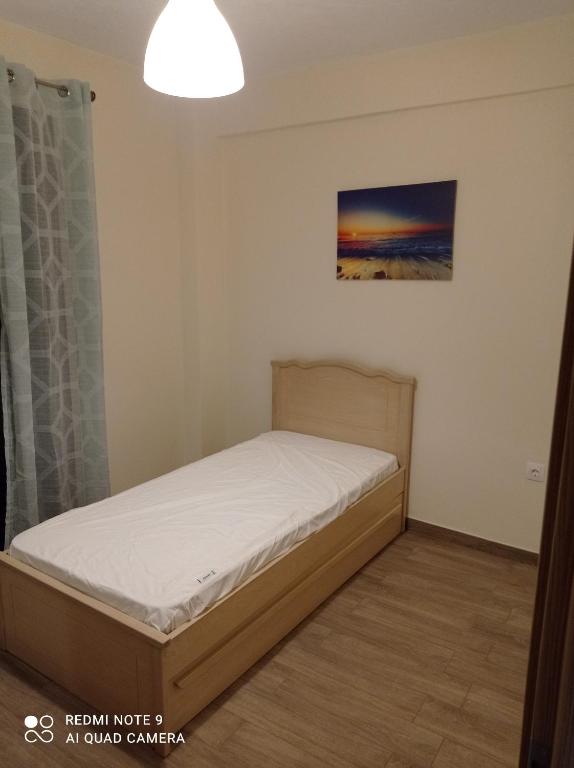 a small bedroom with a bed and a painting on the wall at Sunset Apartment in Epanomi