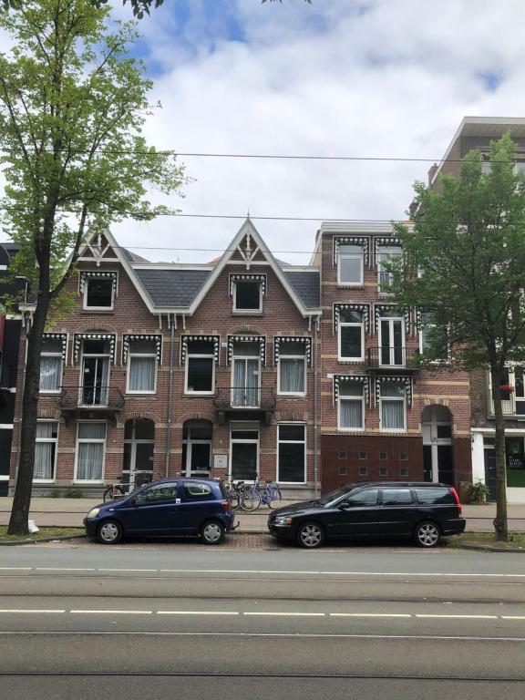 dos coches estacionados frente a un edificio de ladrillo en Frankendael Apartments, en Ámsterdam