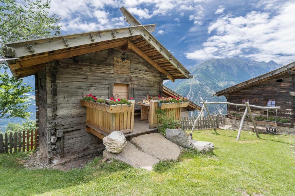 a log cabin with a porch and flowers on it at Kornkammer Lodge - Patleidhof in Naturno