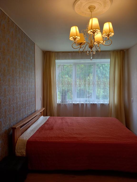 Rātes Vārti Apartamenti في مادونا: غرفة نوم بسرير احمر ونافذة