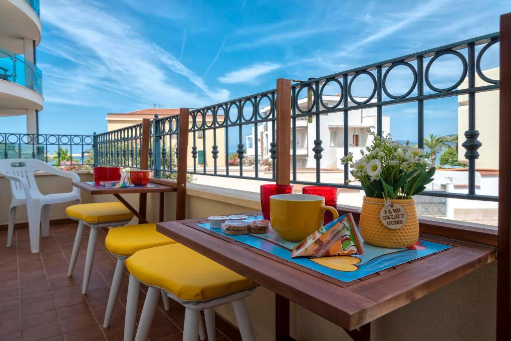 balcón con mesa de madera y sillas amarillas en San Giovanni Lido, en Alghero