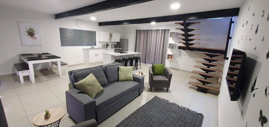 a living room with a couch and a kitchen at Wilgespruit Manor Flat in Roodepoort