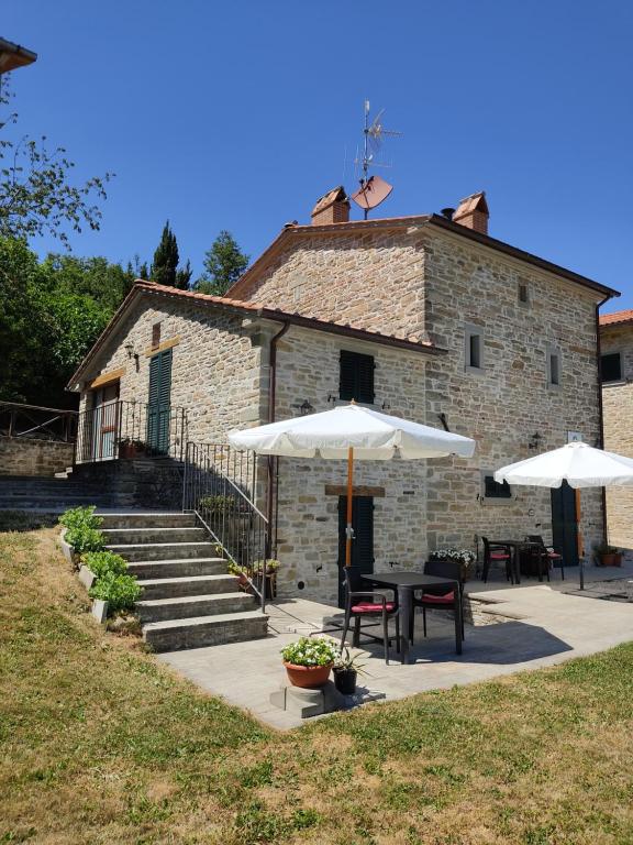 ein Gebäude mit Tischen und Sonnenschirmen davor in der Unterkunft Agriturismo al Monte in San Piero in Bagno