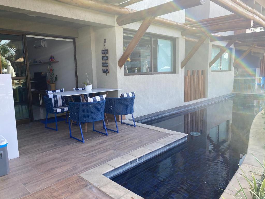 un patio con tavolo, sedie e piscina di Flat Polinésia Térreo Piscina Privativa a Porto De Galinhas