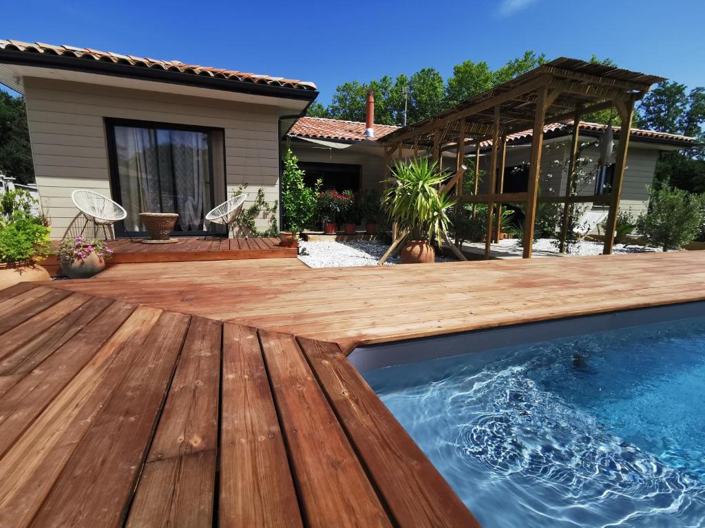 um quintal com um deque de madeira e uma piscina em Maison Balaguera em Saint-Jean-de-Marsacq