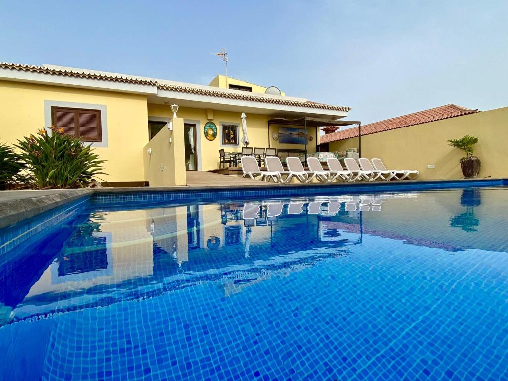 a swimming pool with chairs and a house at Vivienda Vacacional TINIZARA in Arona