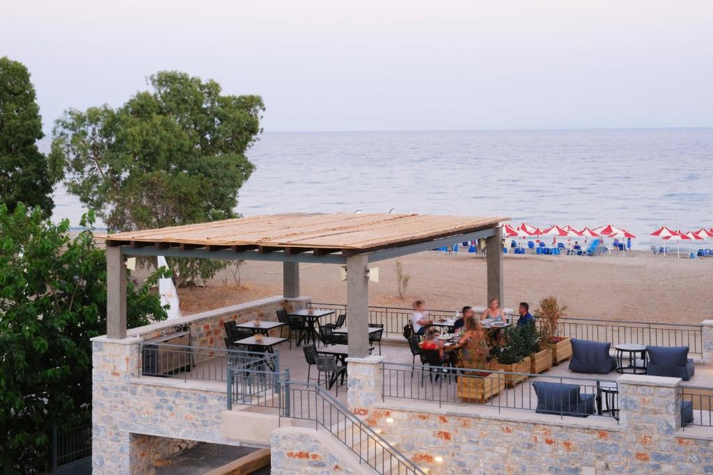 a pavilion at the beach with people sitting at tables at Margo Beach Hotel in Gythio