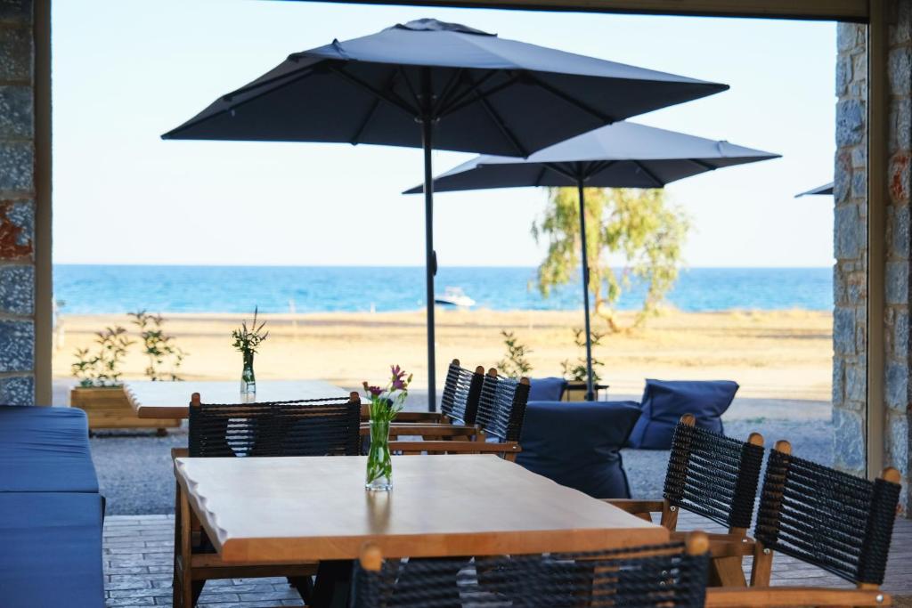 a table with chairs and umbrellas on the beach at Margo Beach Hotel in Gythio