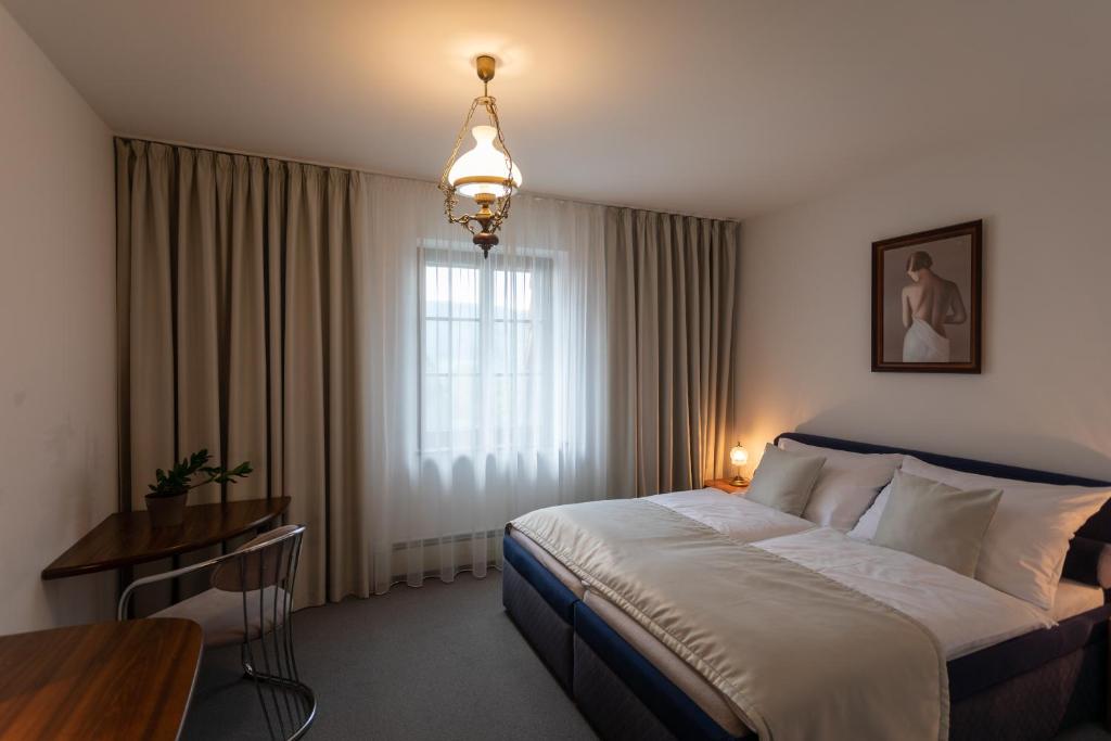 a hotel room with a bed and a table and a window at Hotel Zámeček Pod Hradem Starý Jičín 111 in Starý Jičín