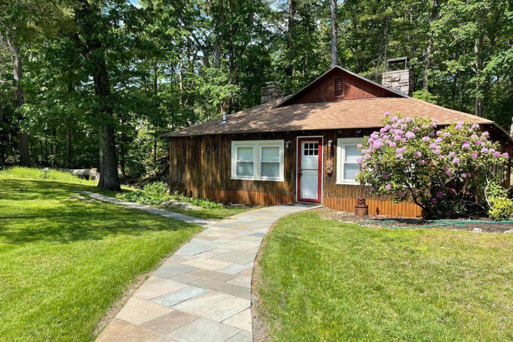 a small cabin with a red door in a yard at Peaceful Getaway Cottage on grounds of historic mid-century gem in Northborough