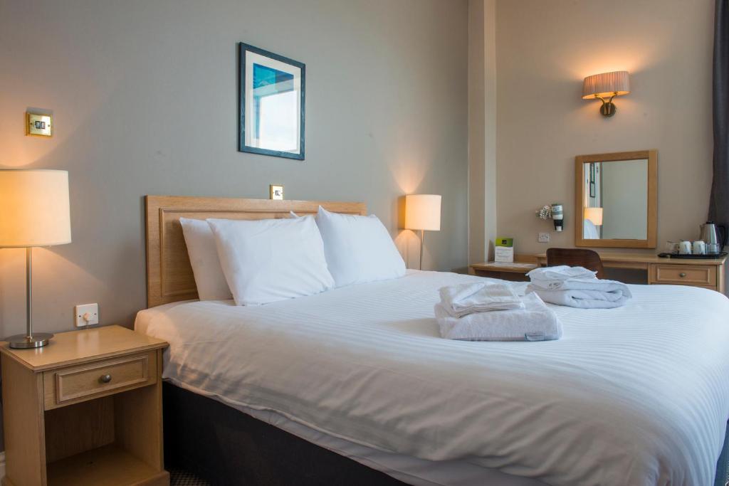 a bedroom with a large white bed with towels on it at Old Colonial, Weston-Super-Mare by Marston's Inns in Weston-super-Mare